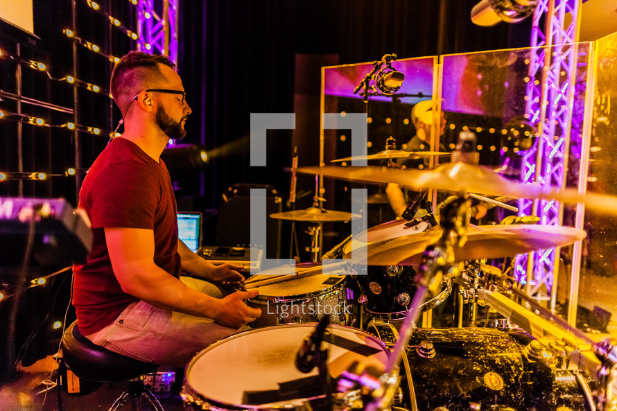 A drummer in a sound studio on stage live worshipping  eyes closed 