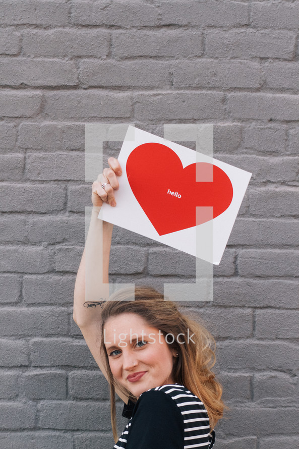 woman holding a picture of a heart that says hello 