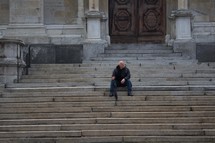 a man sitting and waiting on stone steps 