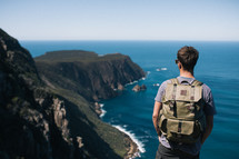 a man backpacking looking out a the view standing on cliffs in New Zealand 