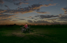 drummer playing in a field at sunset 