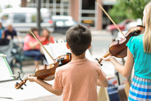 children playing violins outdoors 
