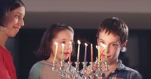 Children lighting colorful Hanukkah candles.