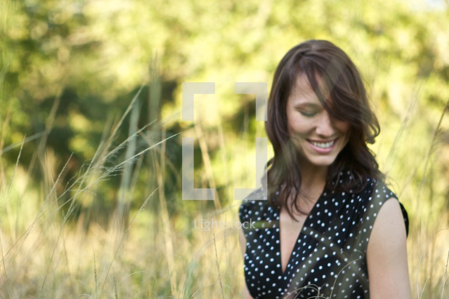 brunette woman smiling in a field