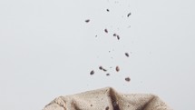 slow motion of coffee beans falling into a large burlap sack