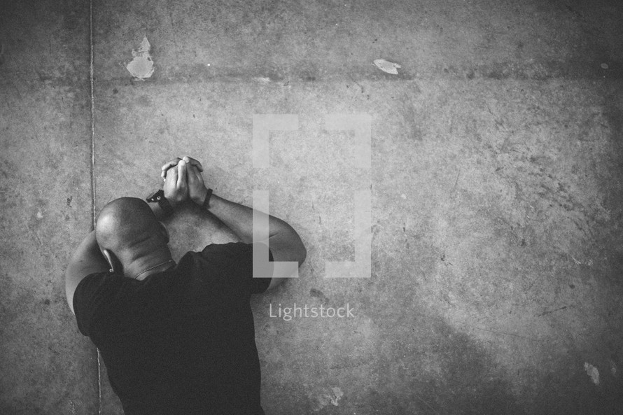 Man lying face down on floor in prayer.