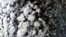 A black and white photograph of cotton ball shaped clouds dotting the sky across the horizon. The Heavens declare the glory of God. When you look at the clouds, they are constantly moving, changing patterns and shapes and forming amazing skyscapes across the horizon that cannot help you see the work of the Creator as He paints the world into existence. 