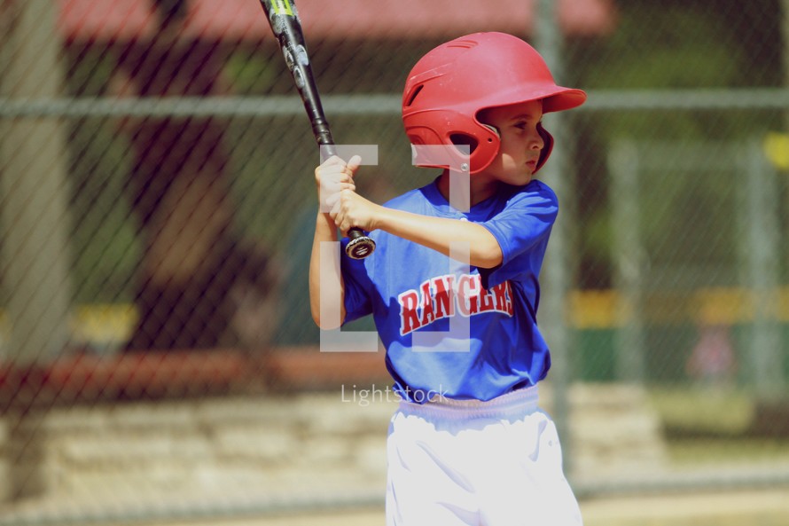 A young boy prepares to swing the bat at a baseball game.