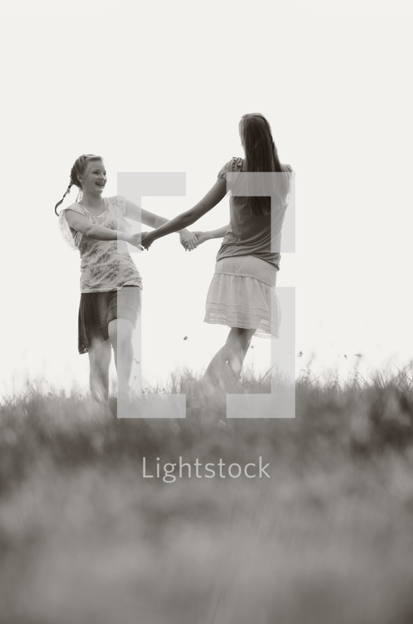 Girls holding hands playing in a field