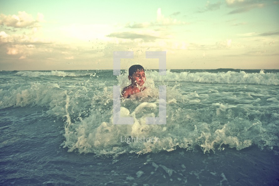 A boy splashing in the waves of the ocean