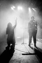 A back view of two people singing and worshiping on stage