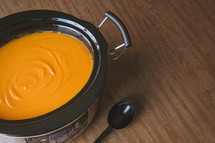 crock pot full of butternut squash soup and spoon 