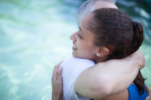 Man and woman hugging in a pool of water.