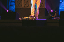 a man on stage with his foot on a guitar pedal 