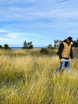 a man walking through a field of tall grass 