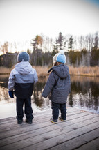 toddlers in coats standing at the end of a pier 
