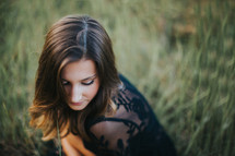teen girl crouching in a field 
