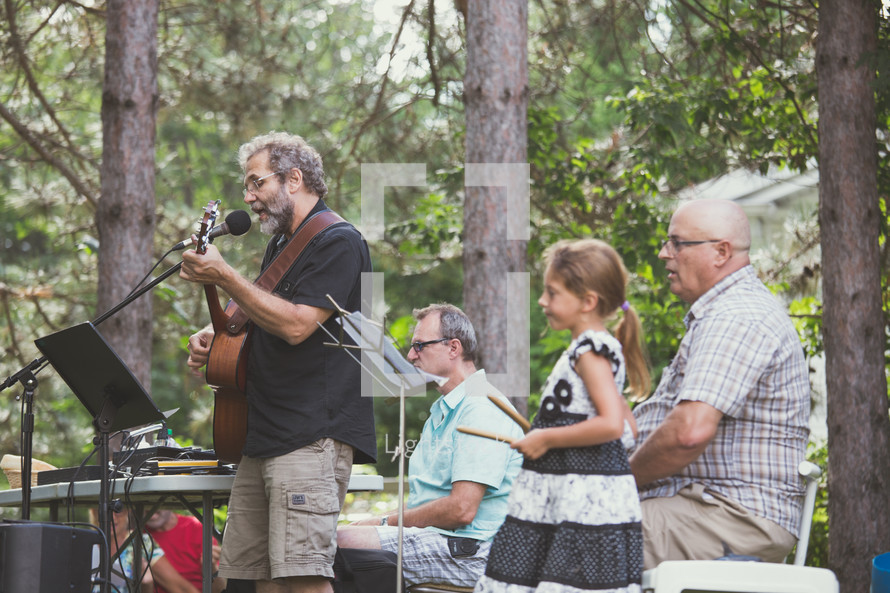 a band spanning generation playing music outdoors 