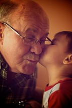 A boy kissing his grandfather on the cheek