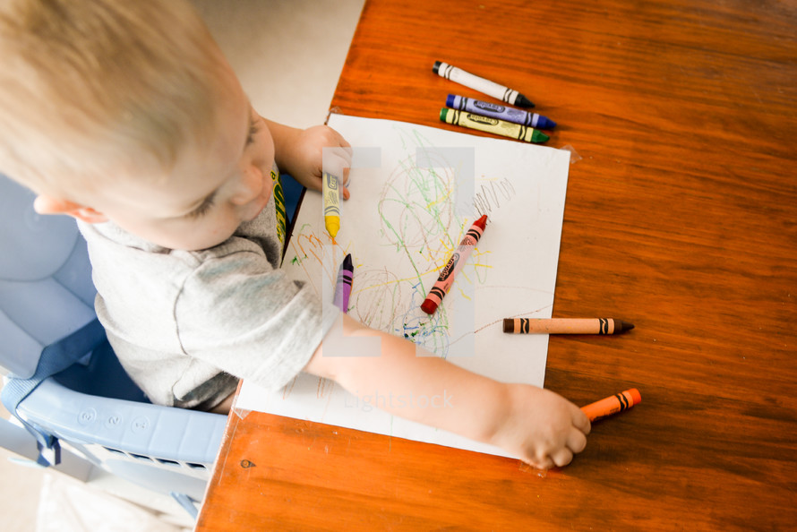 toddler boy coloring with crayons 