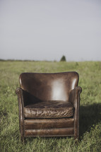a leather chair in a field outdoors 