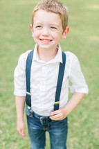 a smiling boy child in jeans and suspenders 