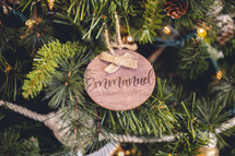 Wooden ornament with the word "emmanuel" on a Christmas tree 