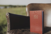 a Bible in a leather chair outdoors 