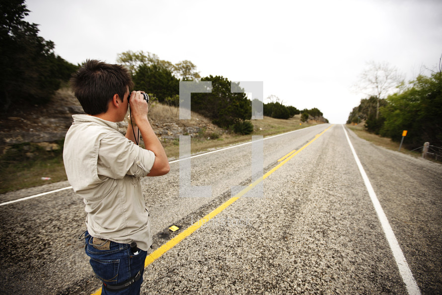 A man takes a picture looking down the highway