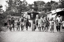man followed by a group of children