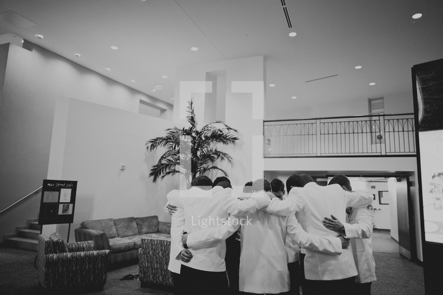 Groomsmen praying with the groom before the wedding