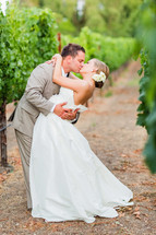 Kissing couple in a napa valley grape vineyard wedding bride groom dip flower in hair