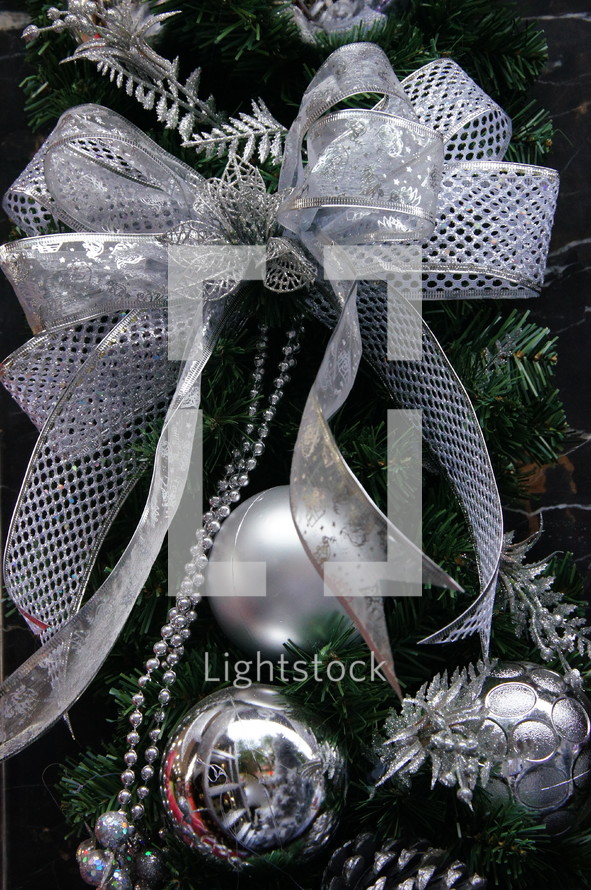 silver bow and ornaments on a Christmas tree