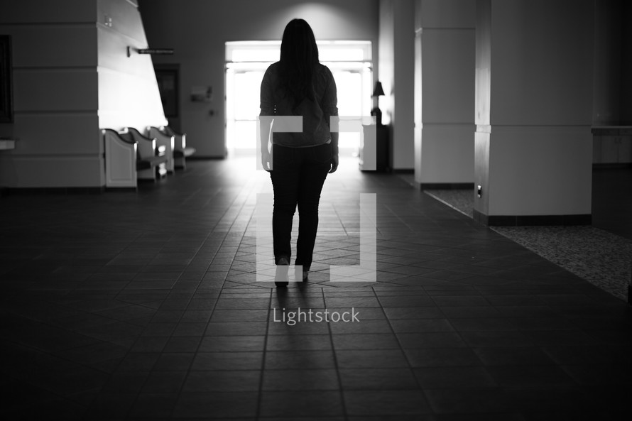 woman with her back to the camera standing in a hallway