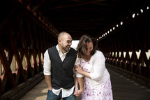 Couple laughing together on a covered bridge.