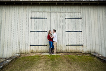 couple hugging in front of a barn 