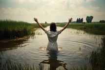 Baptism. Young woman standing in water with her arms outstretched