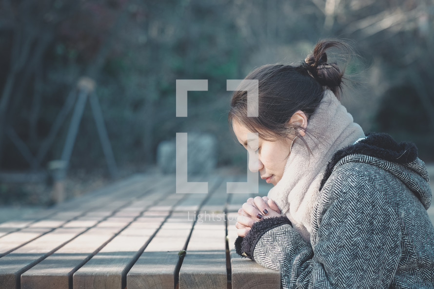 young woman praying alone outdoors 