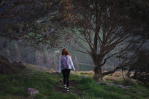 a young woman walking alone through a forest 
