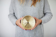 a woman holding a clock 
