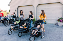 mothers standing together with babies in strollers 