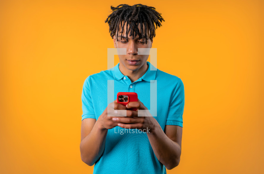 Handsome male teenager surfing internet on smartphone. Man with smile and joy on yellow background. Tech, success, happiness, social networks concept. High quality photo