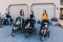 mothers standing together with babies in baby strollers 