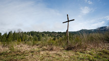 Wide shot of cross with mountains in the background