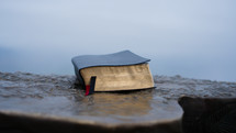 Close up shot of a closed bible on a podium outside on a cloudy day.