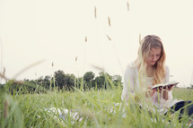 woman sitting outdoors reading a book 