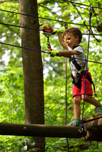 Kids climbing and playing at adventure park holding ropes and climbing wooden stairs