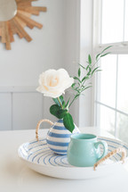 rose in a vase, and mug on a ceramic tray 