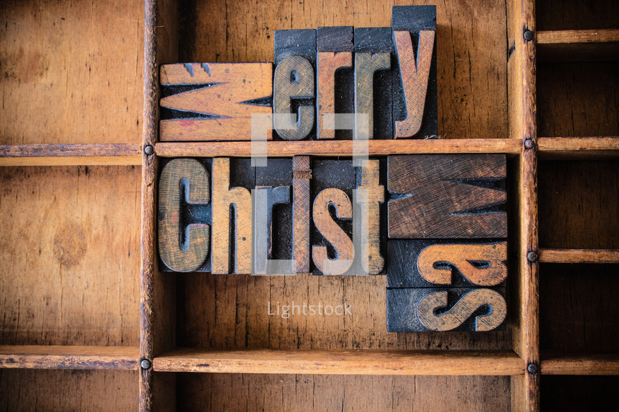 Wooden letters spelling "Merry Christmas" on a wooden bookshelf.
