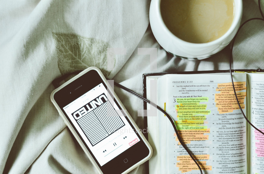 podcast and open Bible on a bed 